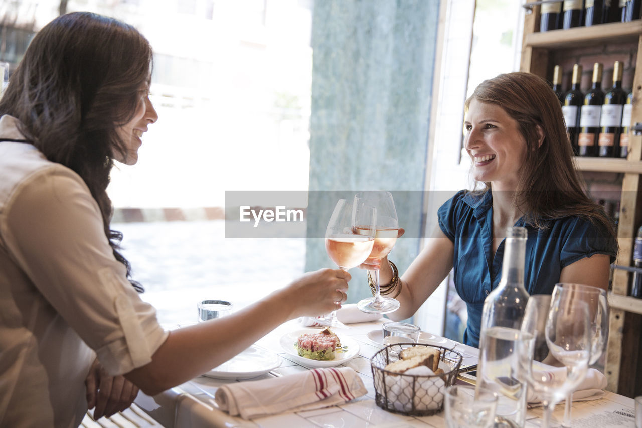 Women toasting wineglasses while sitting in restaurant