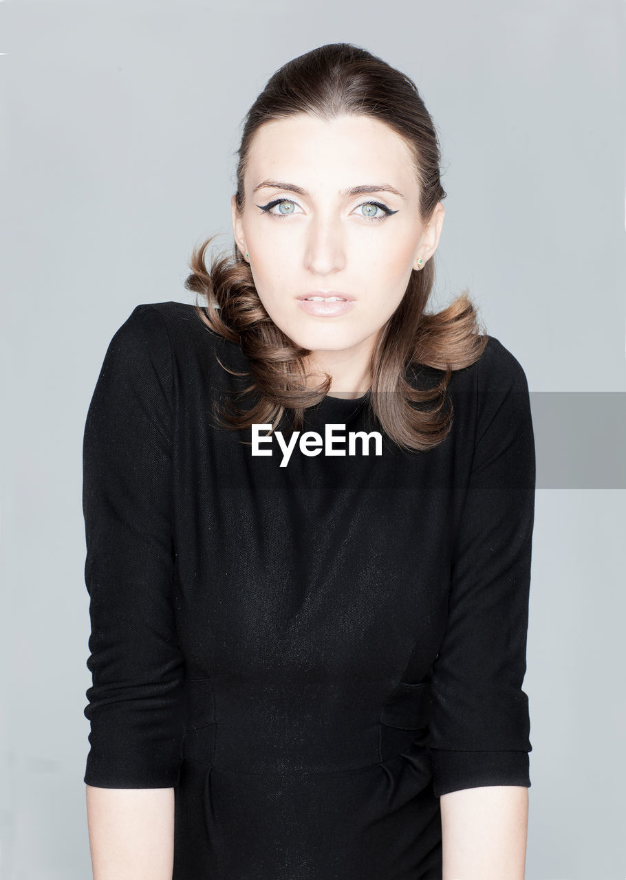Portrait of beautiful young woman against gray background