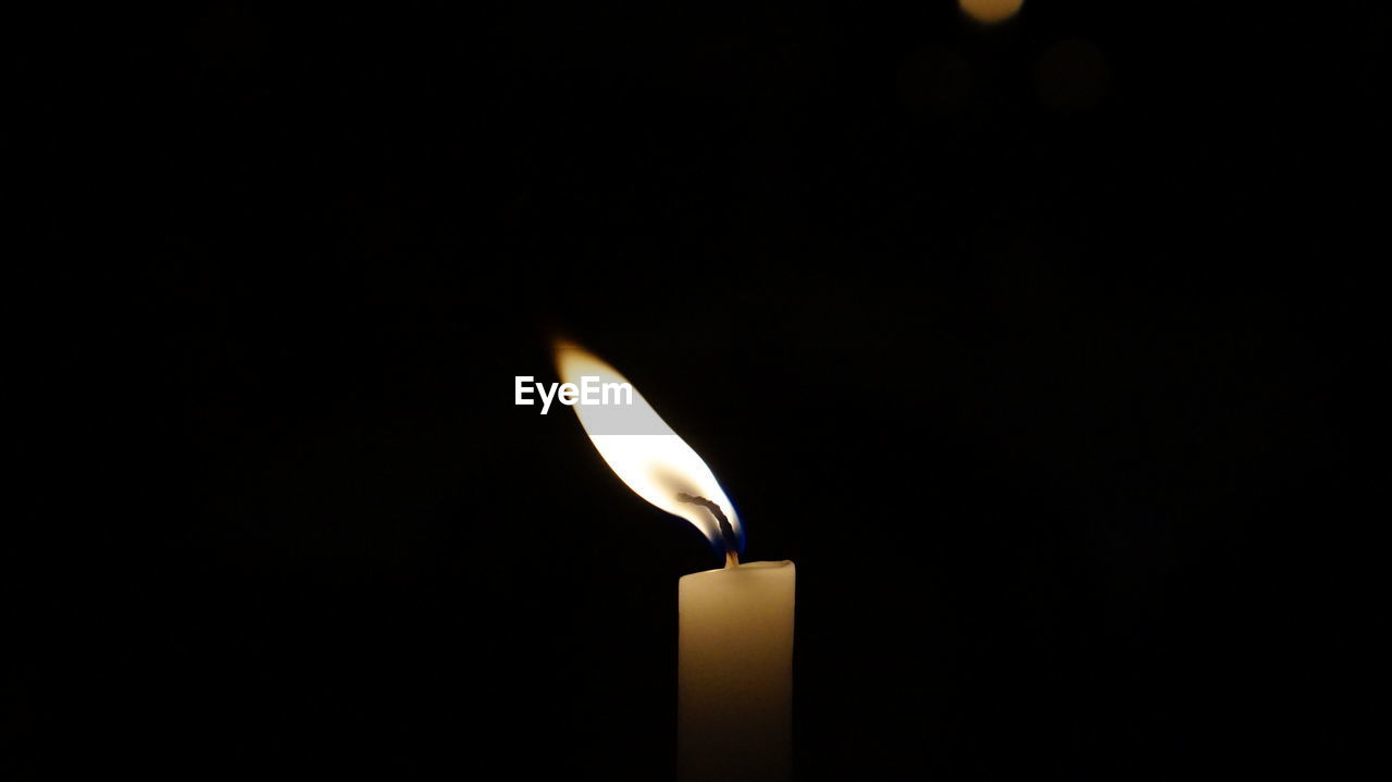 Close-up of lit candle in darkroom