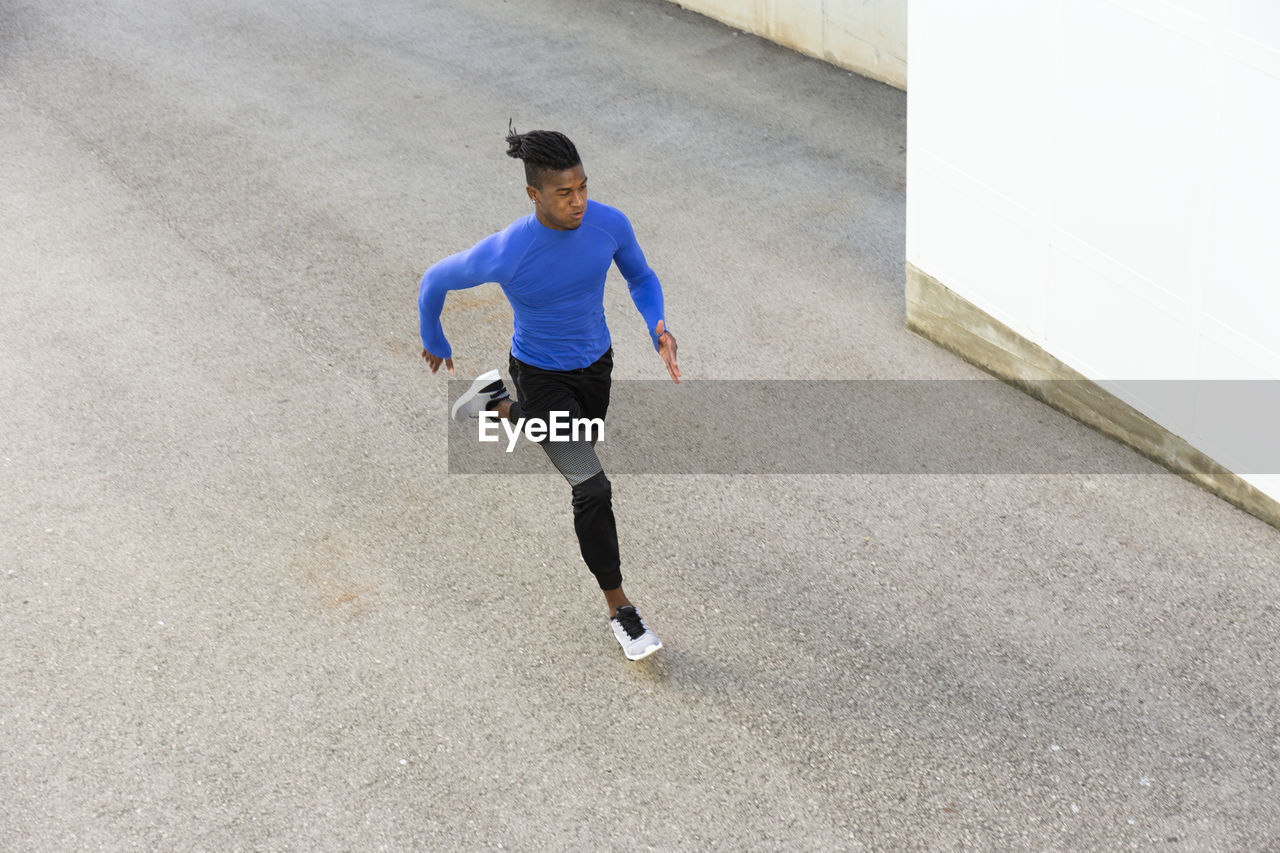 Determined young man running on footpath