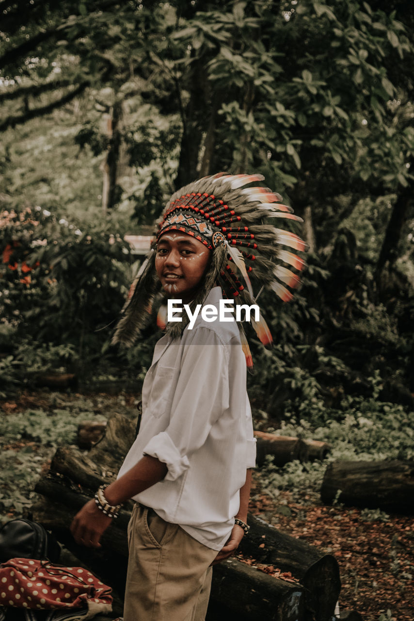 Portrait of smiling man wearing headdress in forest