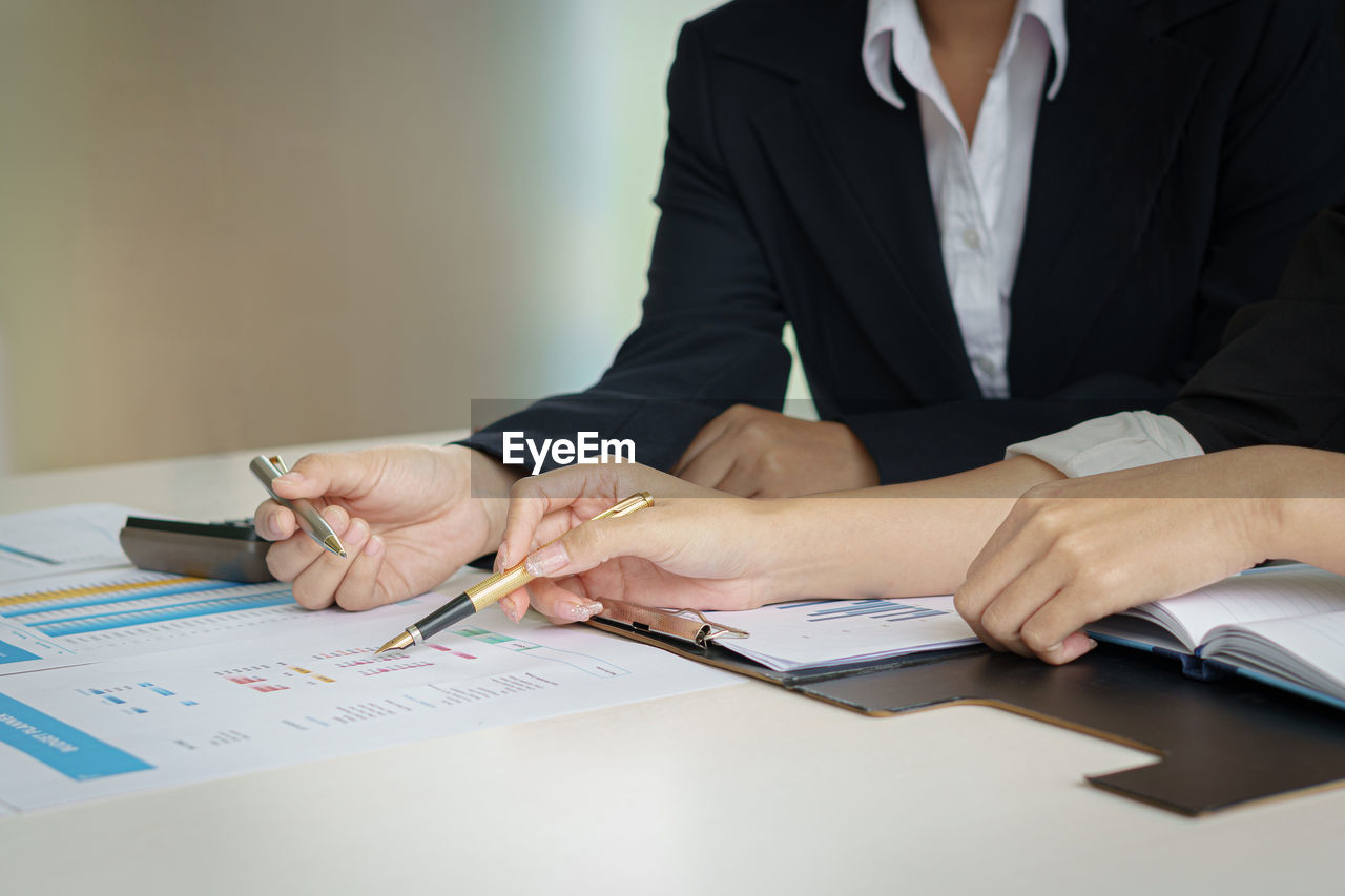 Business woman and partner hand pointing at finance chart for planning about  tax, accounting, 