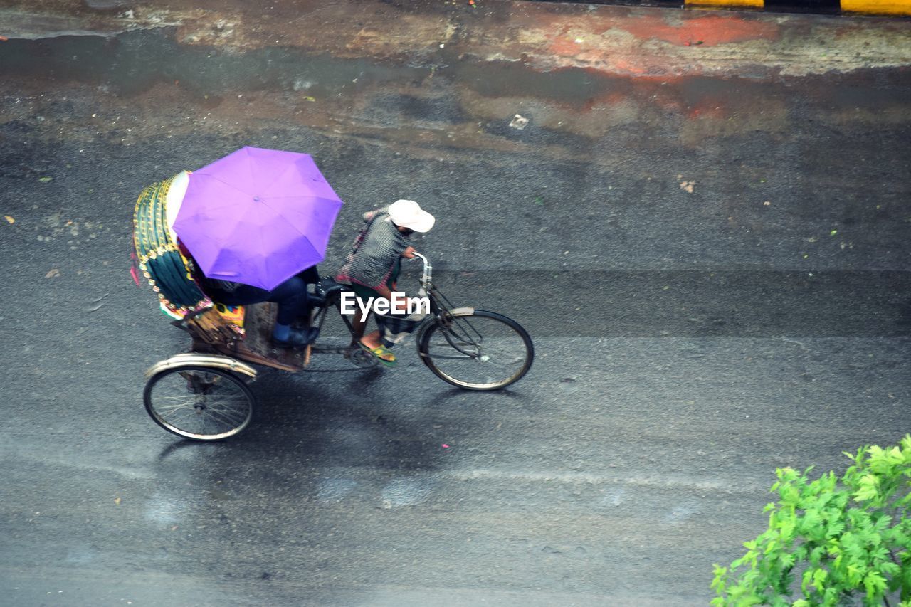 HIGH ANGLE VIEW OF PERSON RIDING BICYCLE ON ROAD