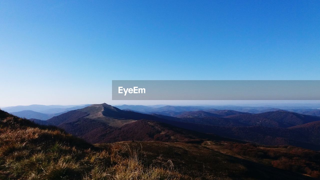 Scenic view of mountains against clear blue sky