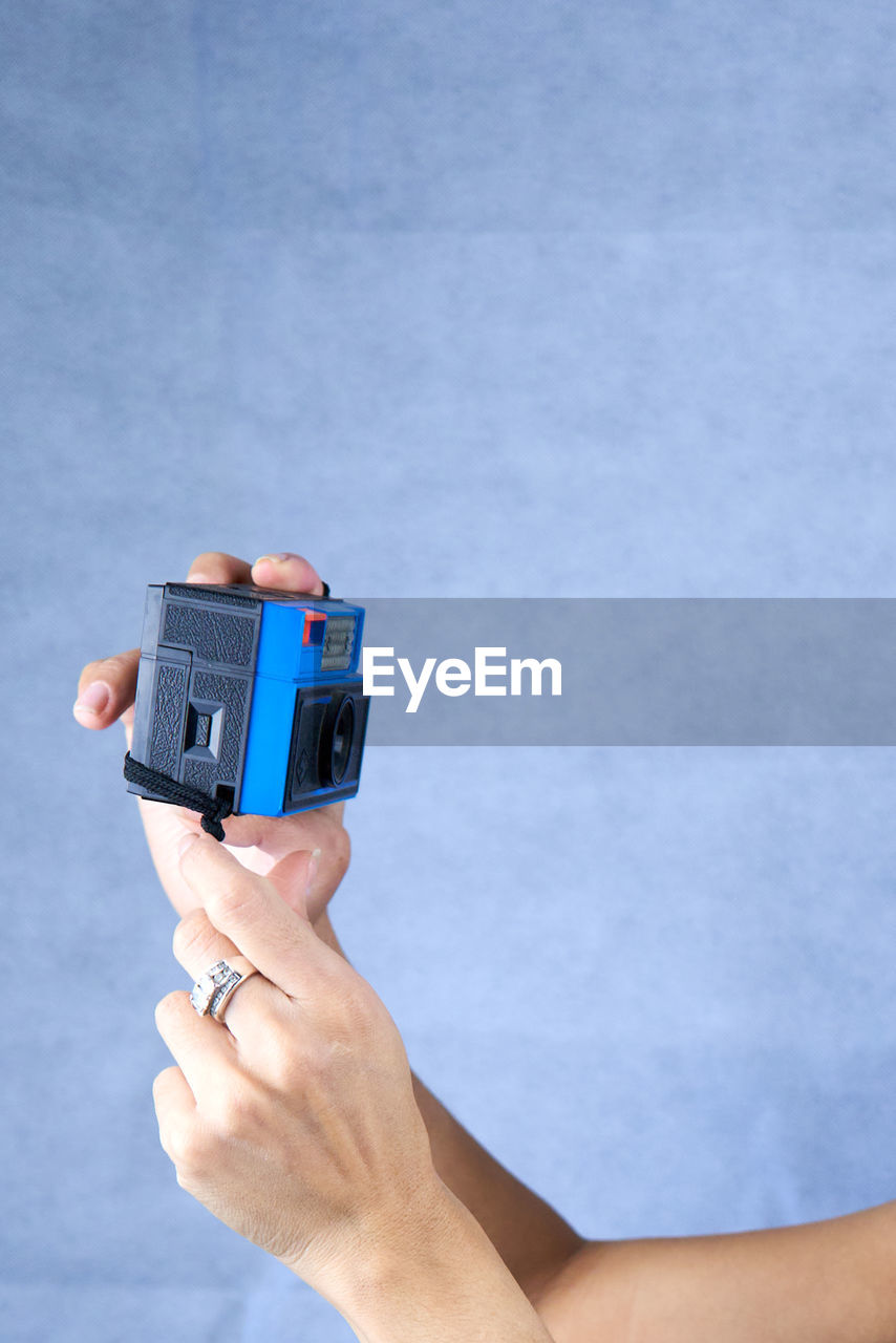 Close-up rear view of woman's hands holding vintage film camara.