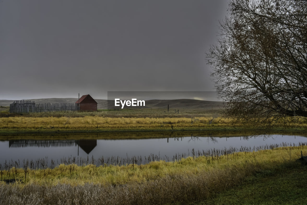 Scenic view of field by lake against sky