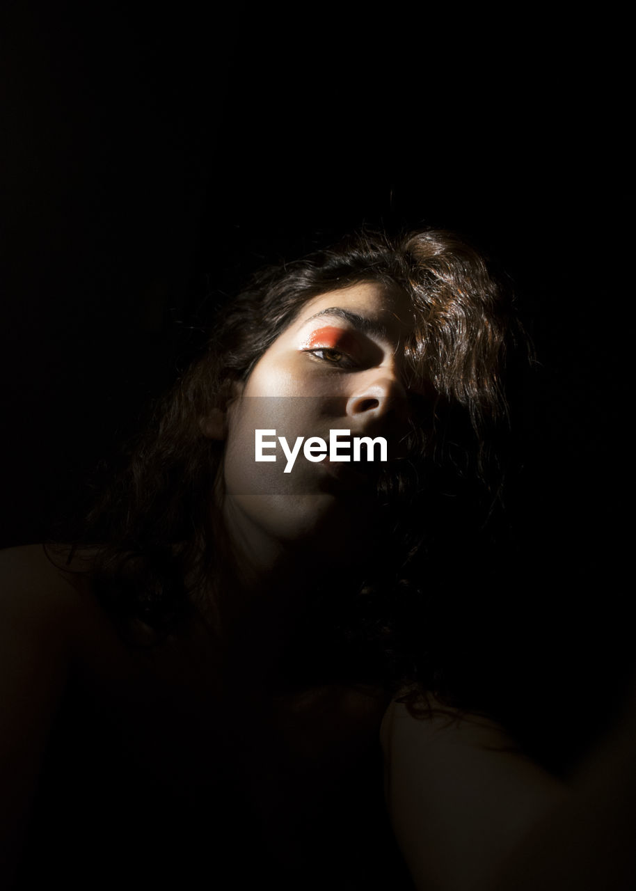 Portrait of young woman against black background