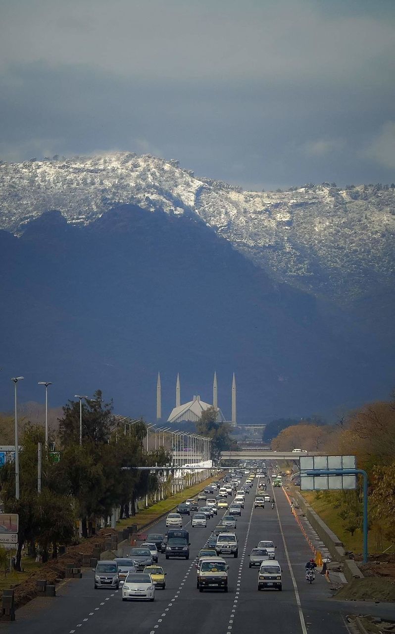 Cars on road against snowcapped mountain 