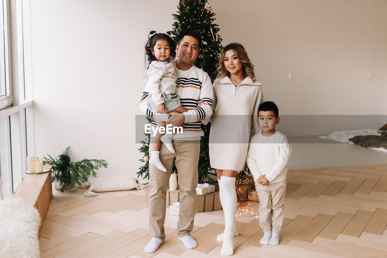 An asian multi-racial family with two children celebrate the christmas holiday in a decorated house