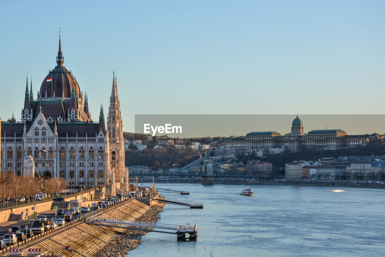 Hungarian parliament building by danube river against clear blue sky