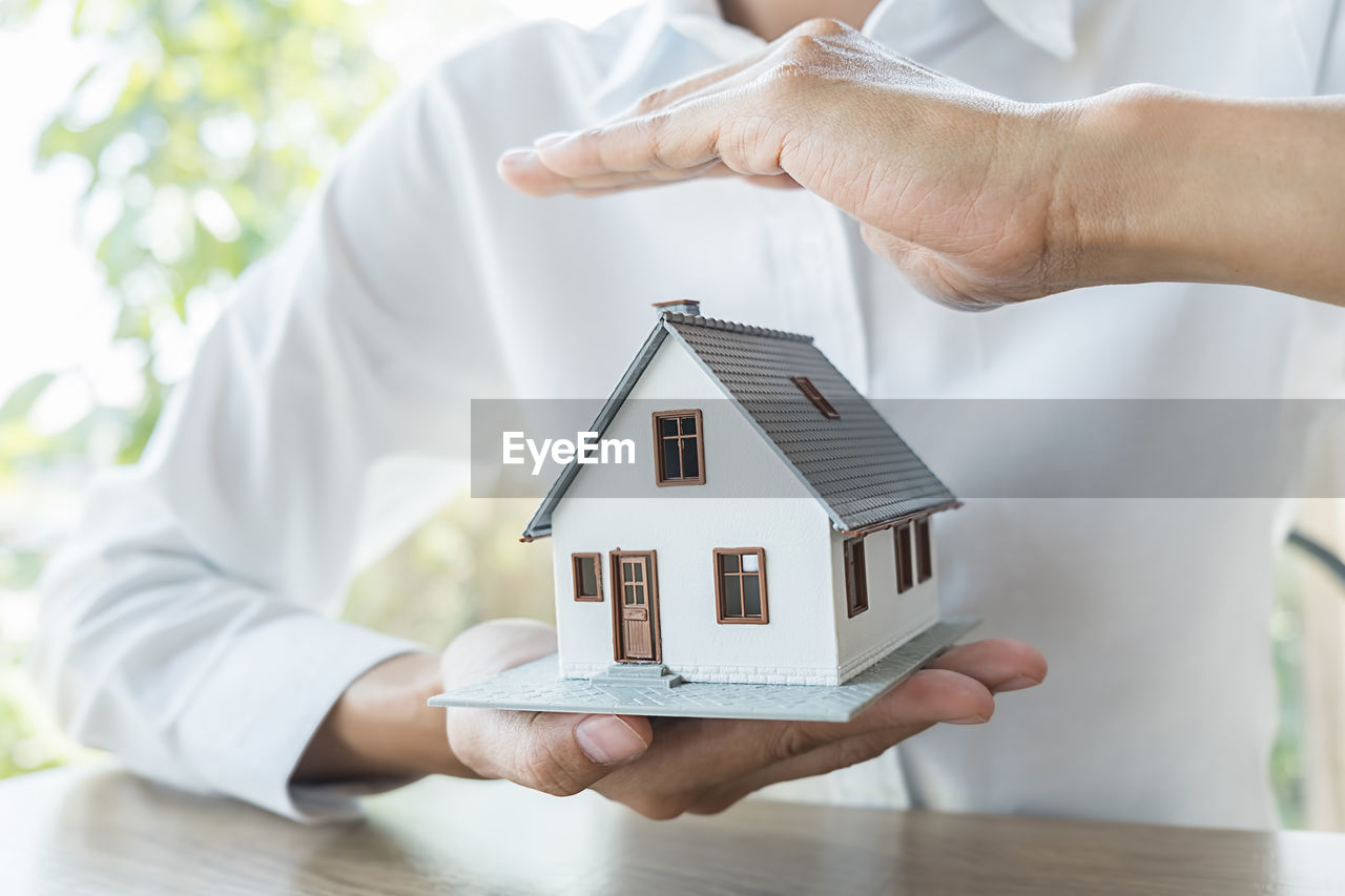 MIDSECTION OF PERSON HOLDING PAPER OUTSIDE HOUSE