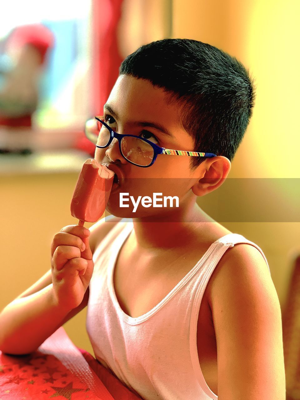 Boy looking up while eating ice cream at home