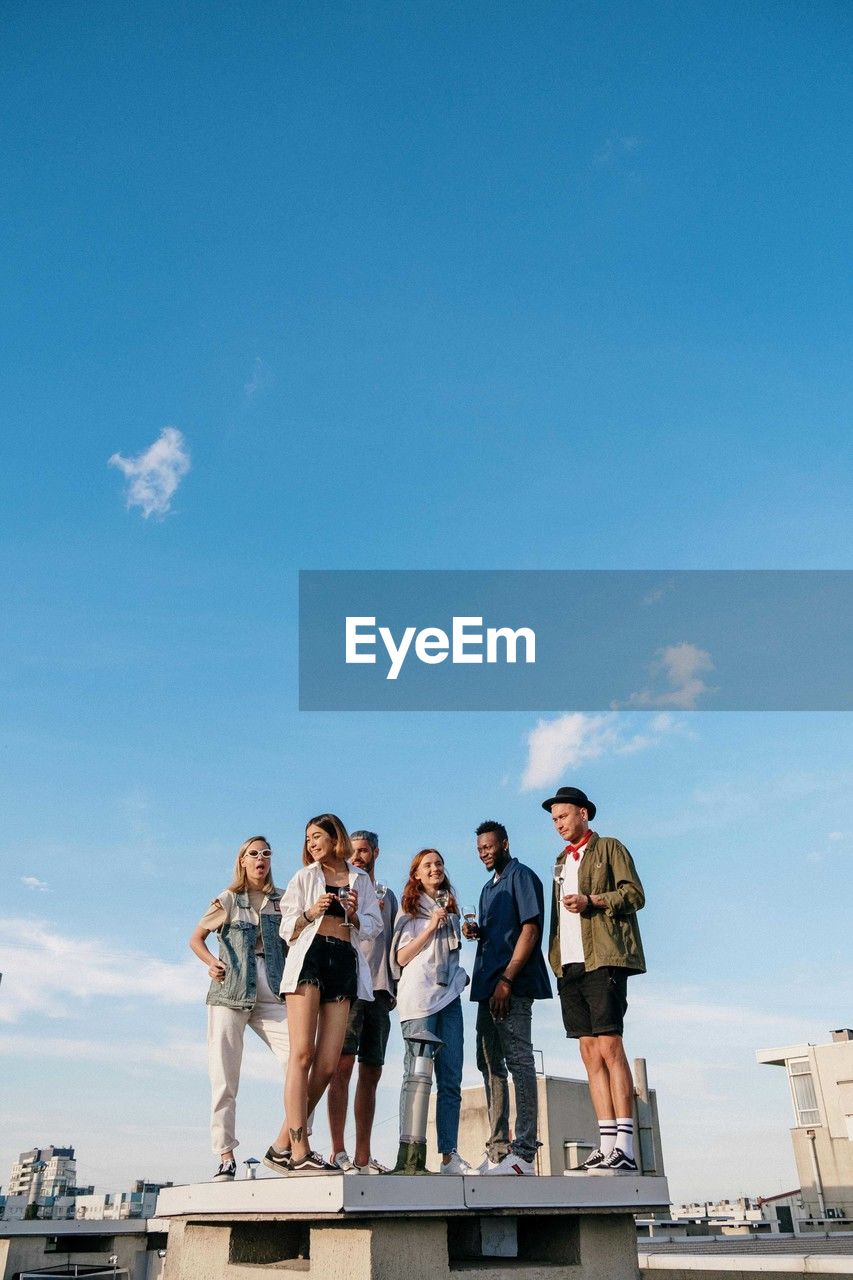 group of people, sky, men, adult, women, togetherness, copy space, vacation, blue, architecture, nature, young adult, female, friendship, day, standing, full length, happiness, cloud, water, low angle view, child, outdoors, casual clothing, sea, leisure activity, fun, smiling, emotion, person, sunlight, enjoyment, lifestyles