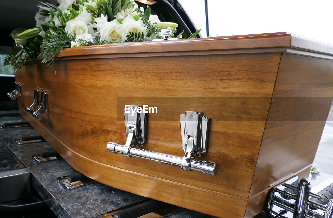 Closeup shot of a funeral casket or coffin in a hearse or chapel or burial at cemetery
