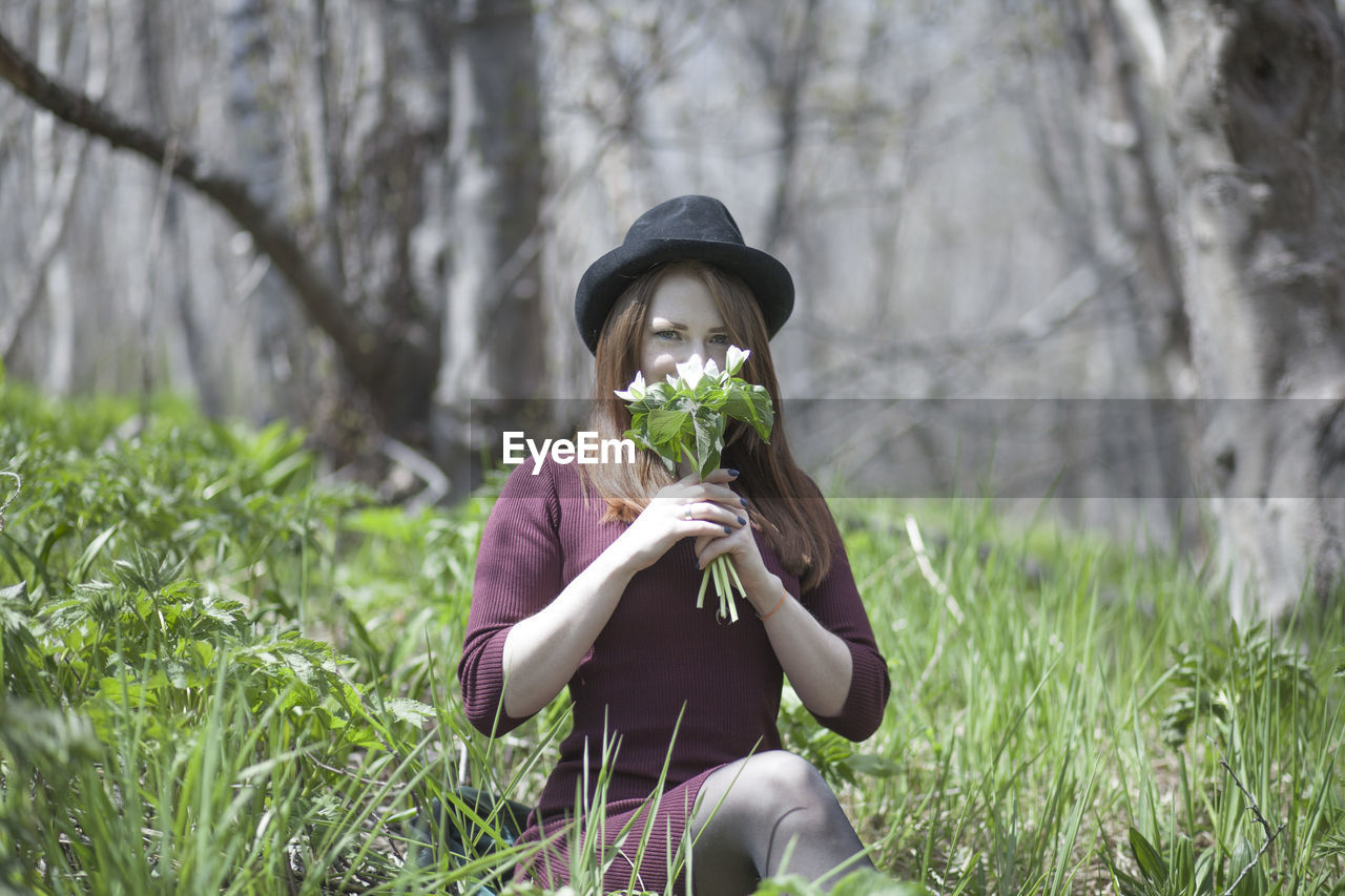 Portrait of young woman holding hat on land