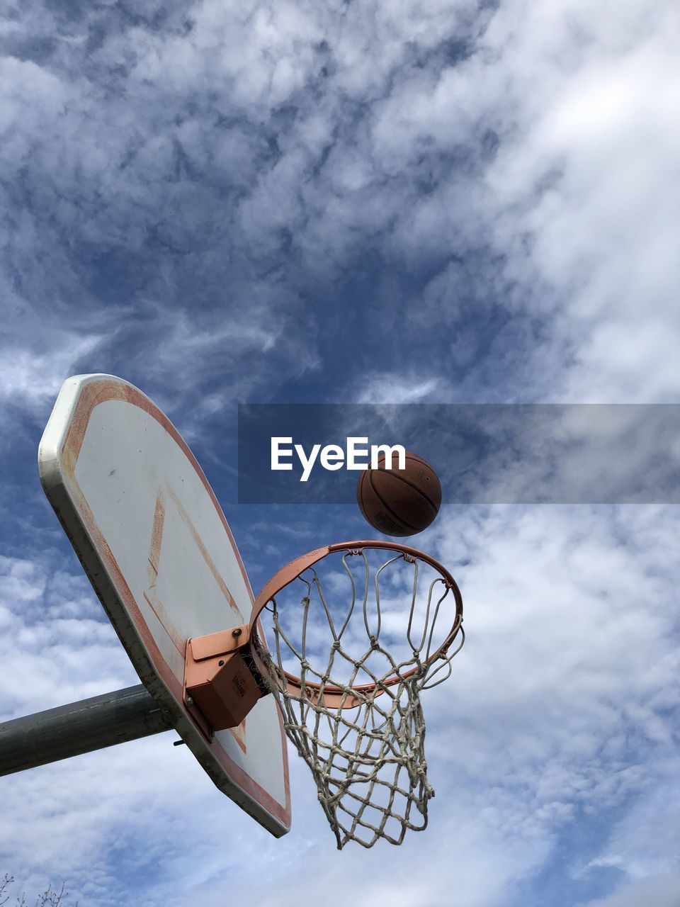 Low angle view of basketball hoop and ball against a blue sky