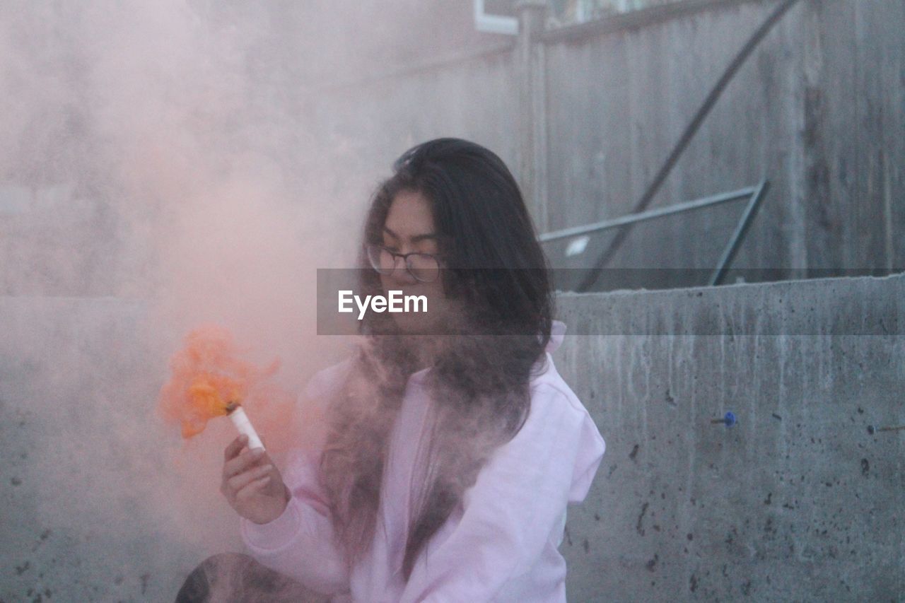 Woman holding smoke bomb at construction site