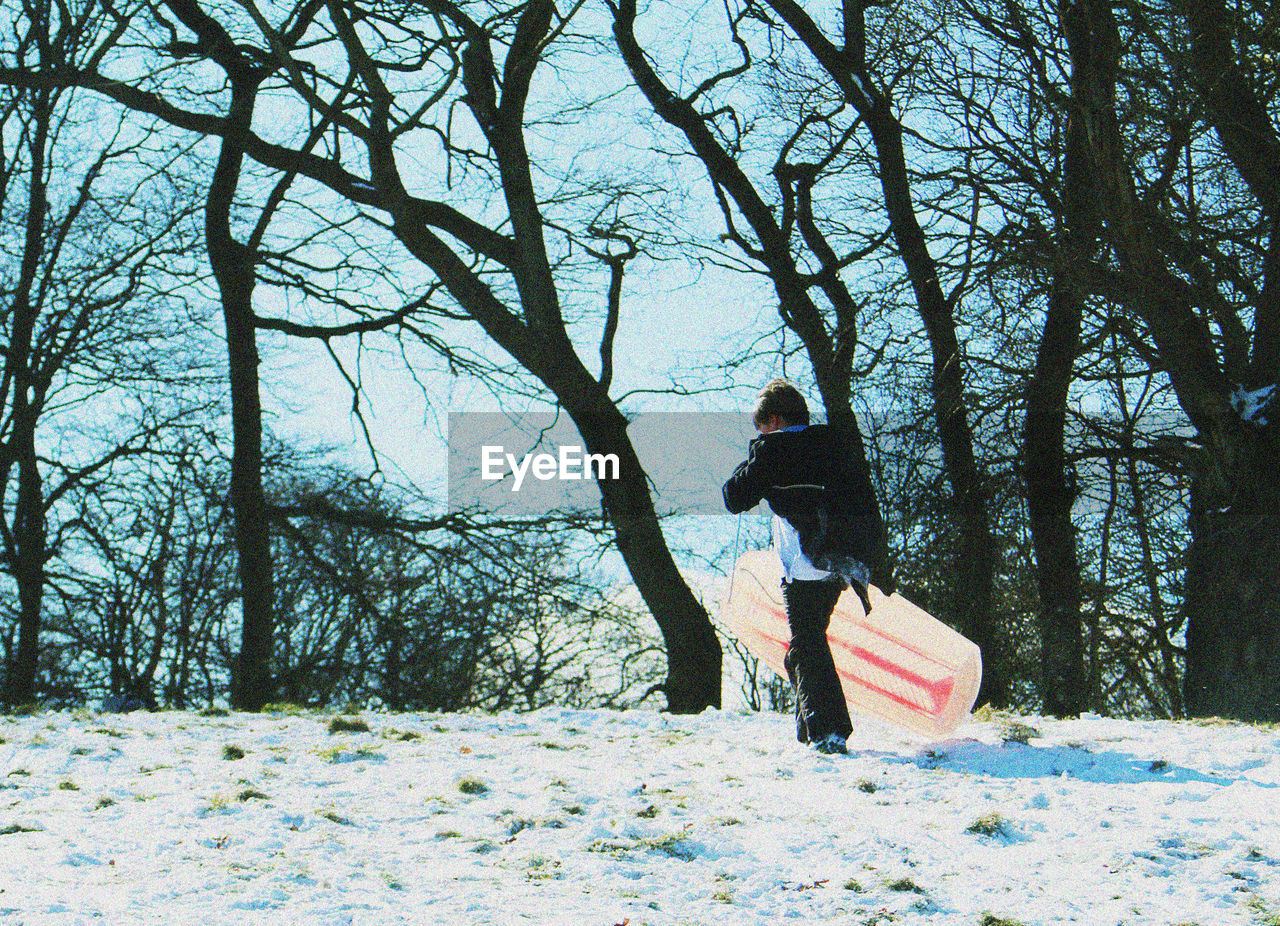 MAN WALKING ON BARE TREES IN FOREST DURING WINTER