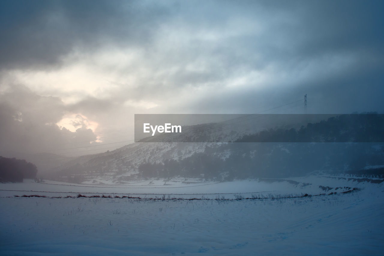 Snowy landscape where the sun's rays pass through deep clouds