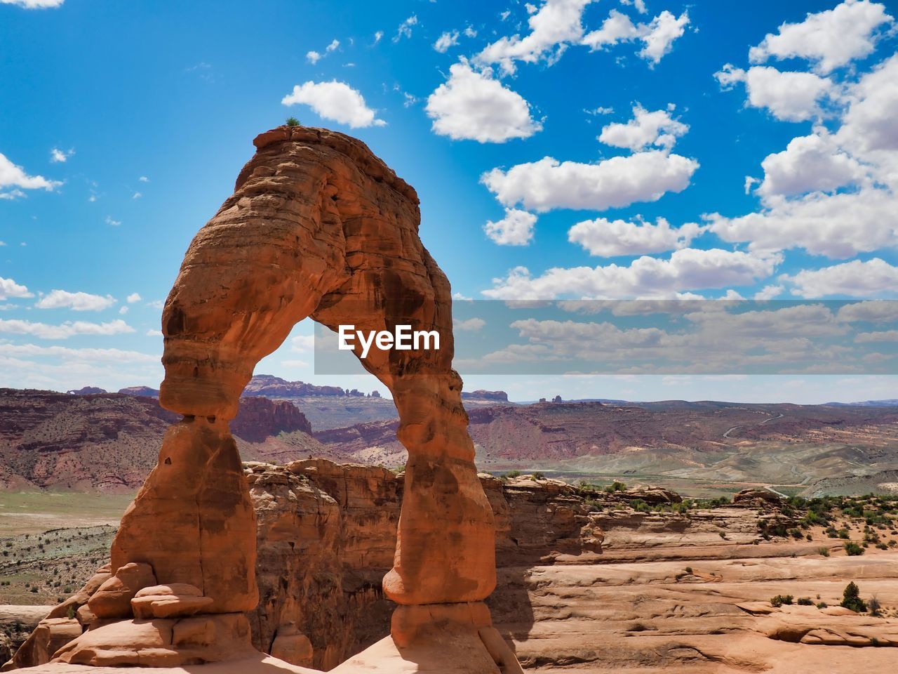 Delicate arch on landscape against cloudy sky