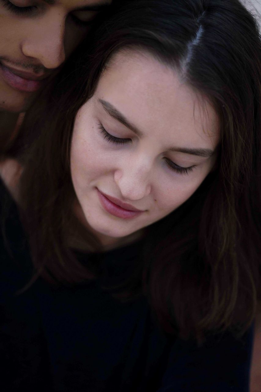 Close-up portrait of young woman sitting next to her boyfriend