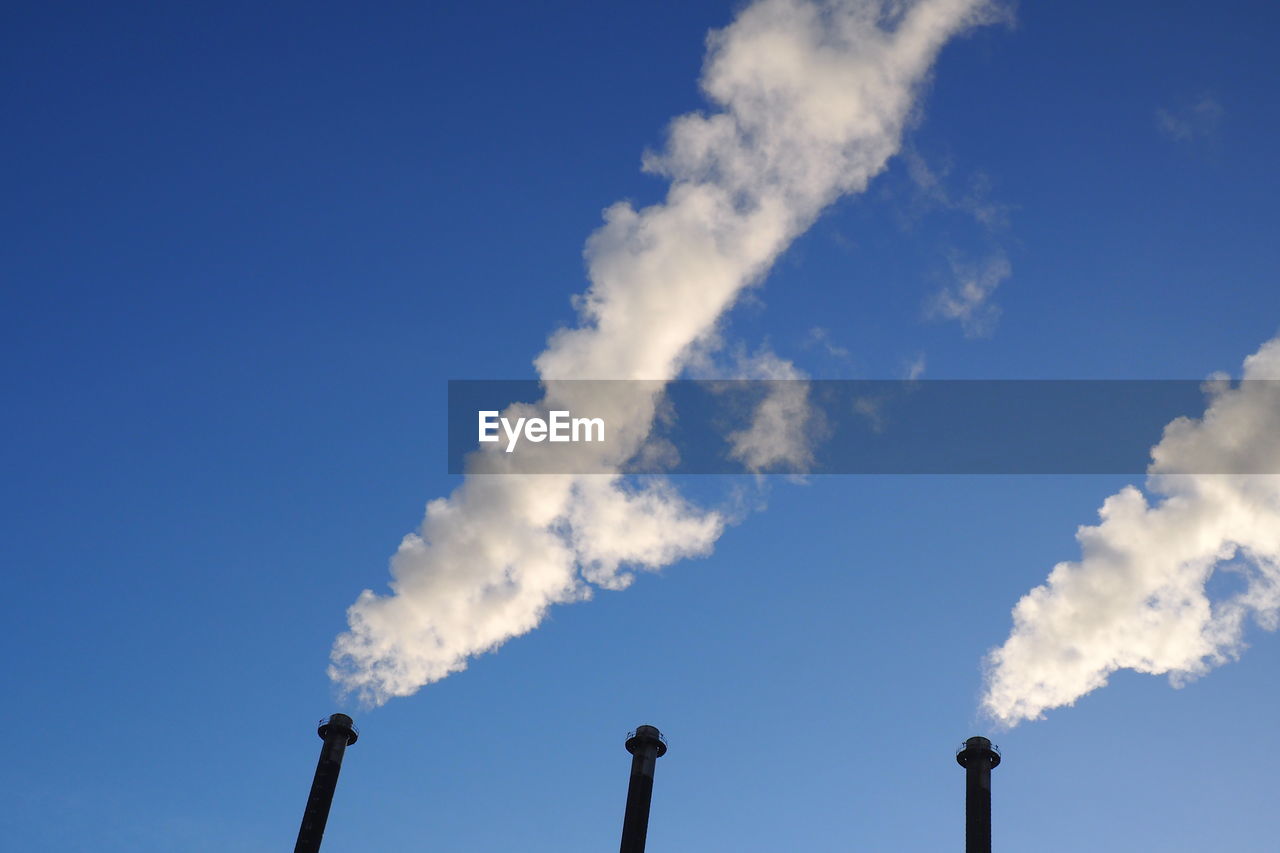 Low angle view of smoke stack against blue sky