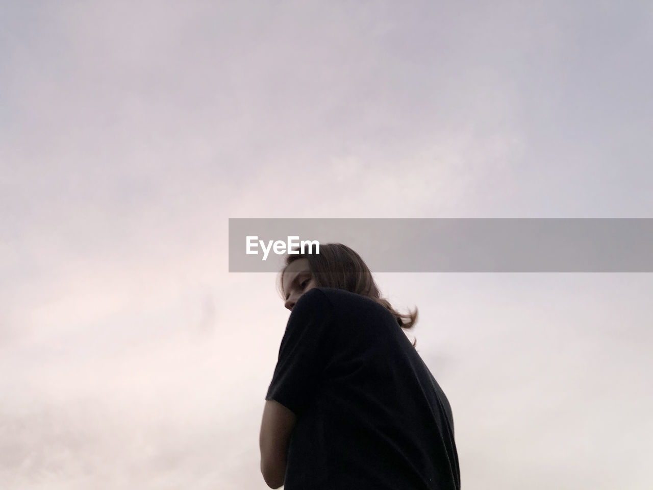 Low angle portrait of woman standing against sky