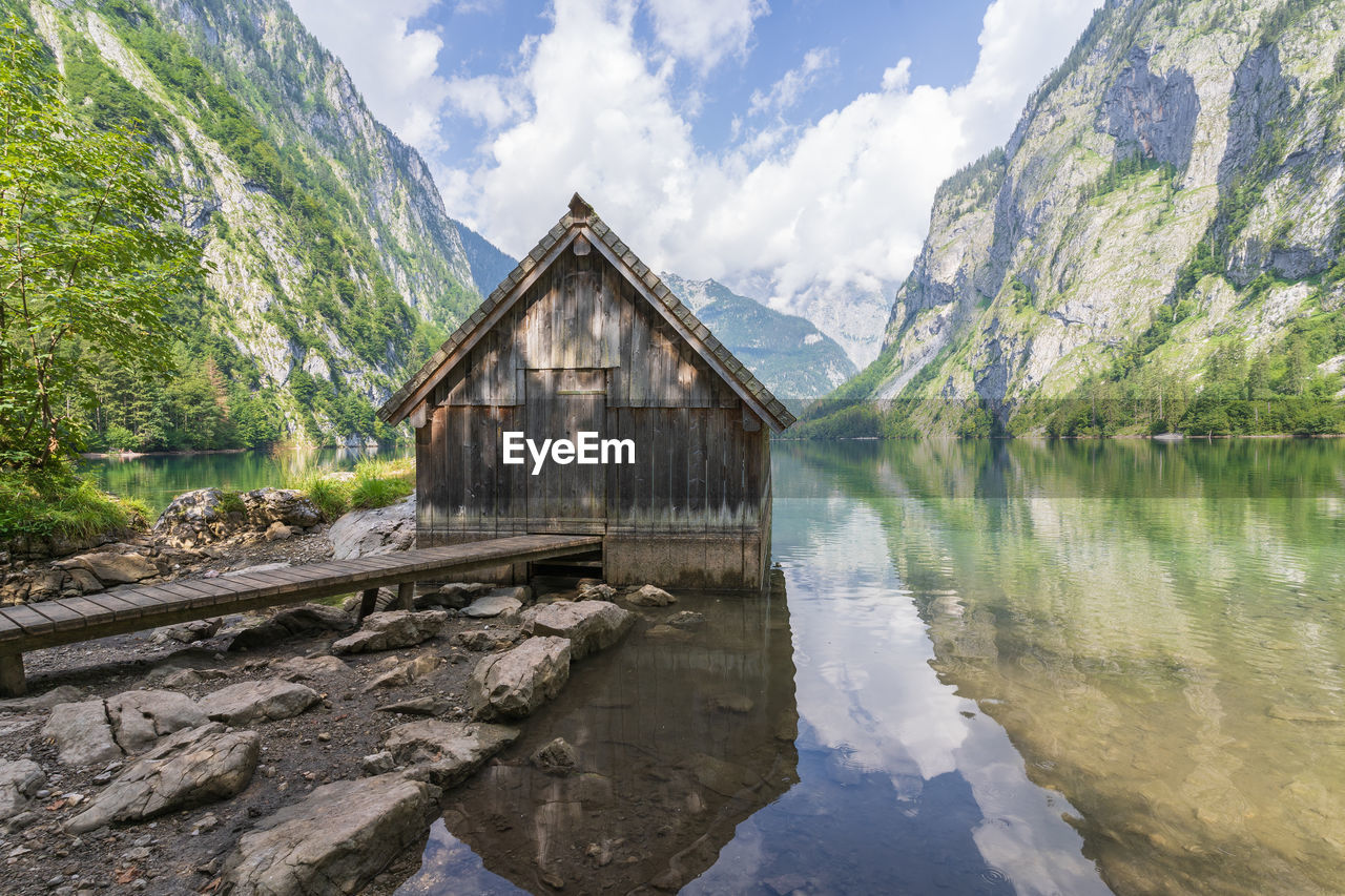 Old wooden boathouse on a still pristine alpine lake surrounded by mountains, obersee, germany