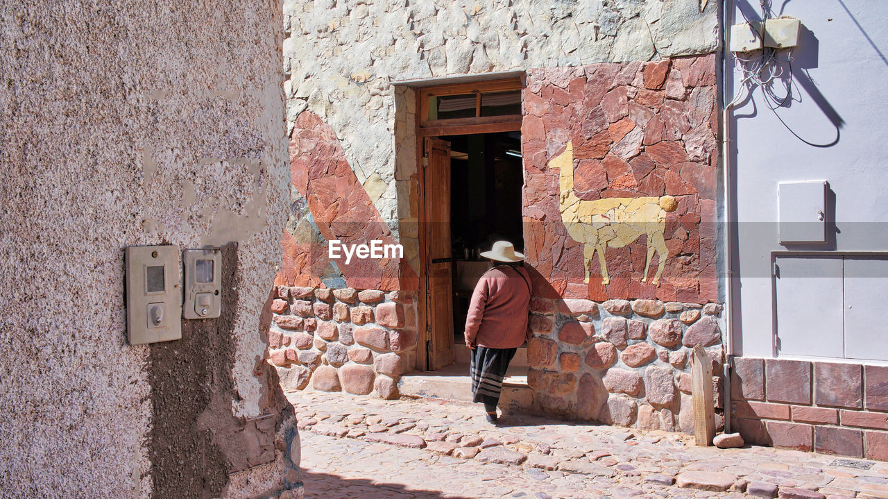 REAR VIEW OF MAN STANDING BY DOOR OF BUILDING