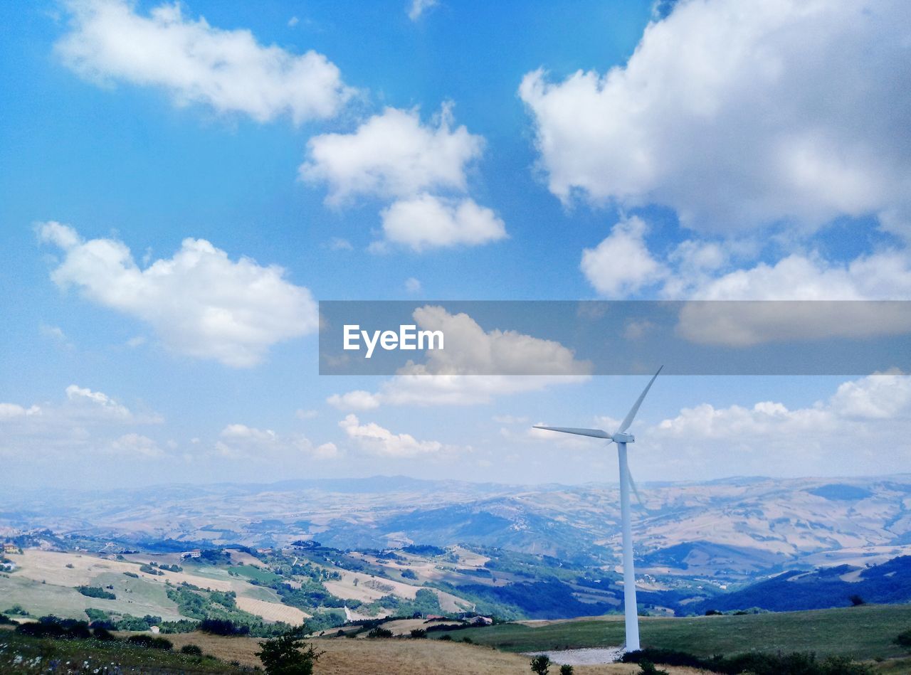 Wind turbines on field against sky