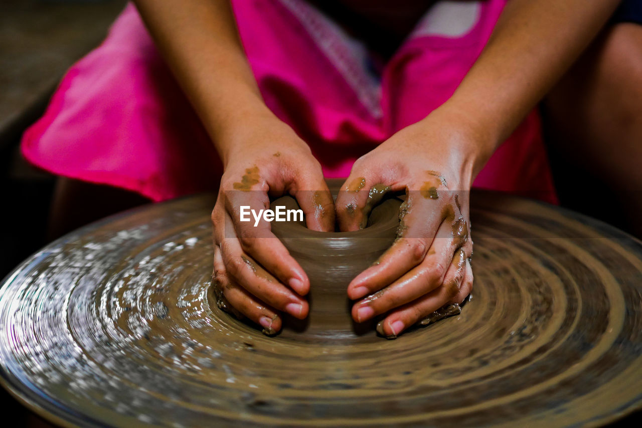 Midsection of woman making pottery in workshop