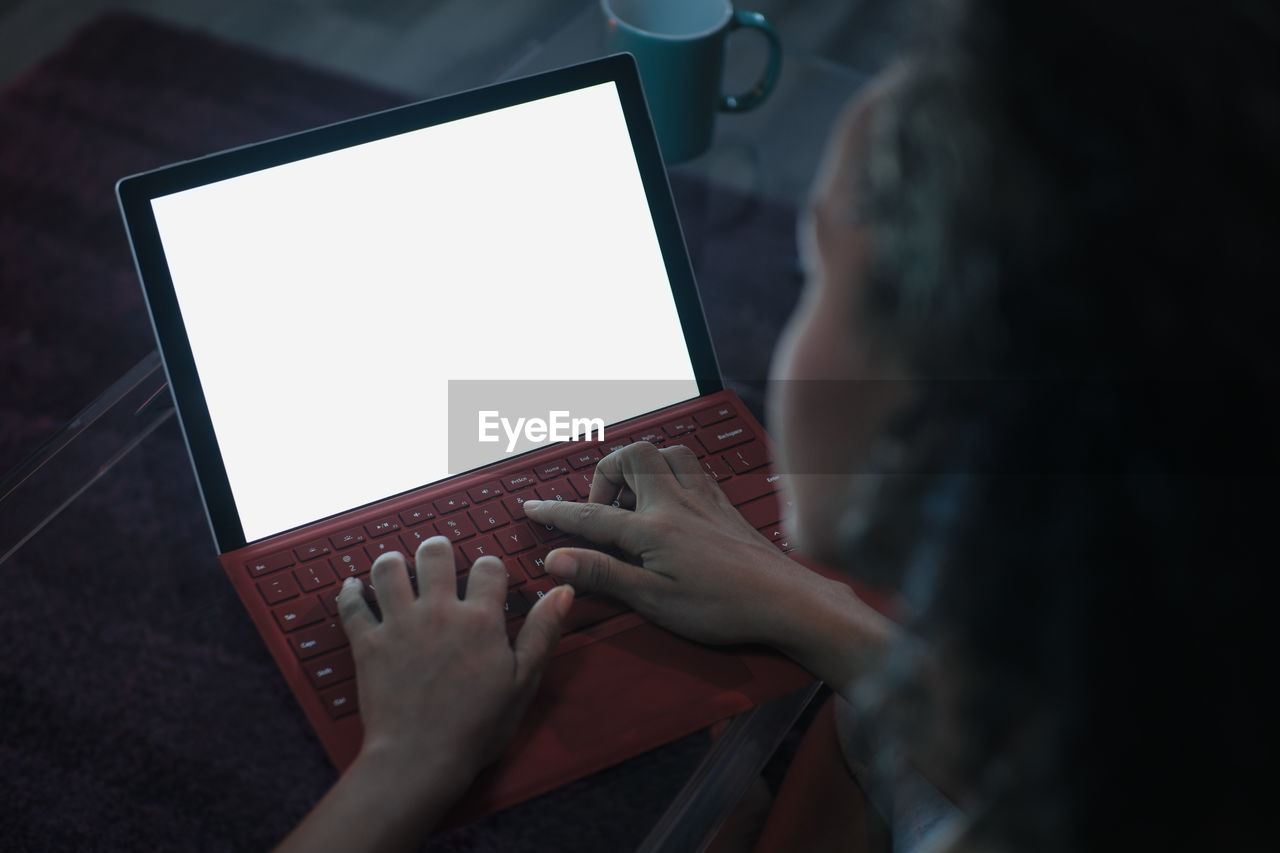 High angle view of young woman using laptop on table at home