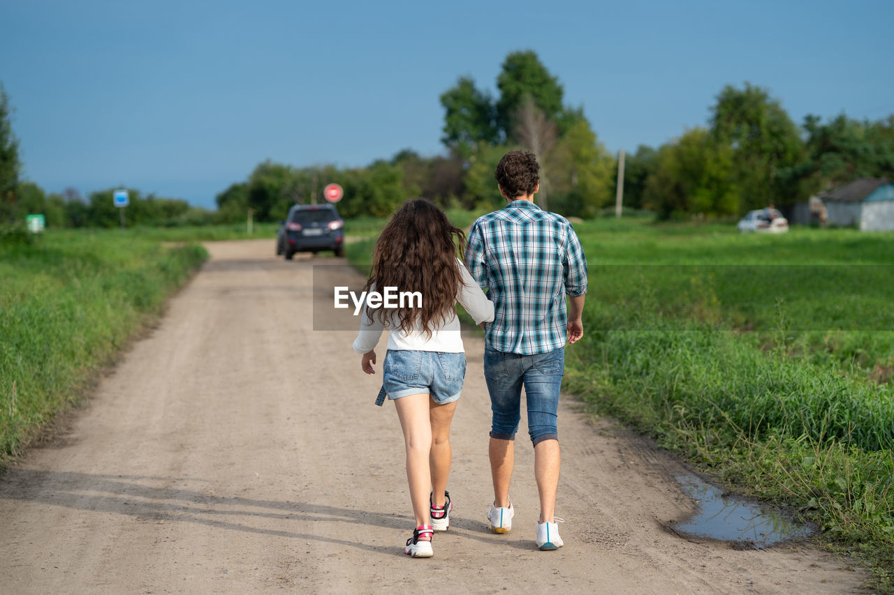 REAR VIEW OF WOMEN WALKING ON ROAD