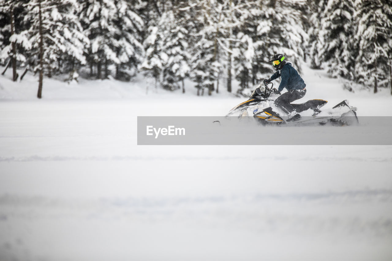 Active man snowmobiling through deep snow during weekend getaway.