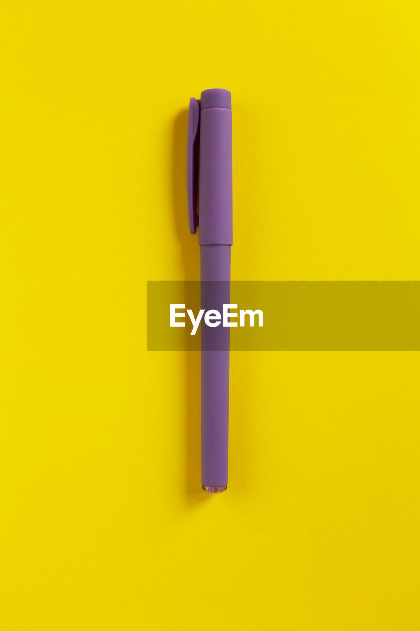 Directly above shot of pen on yellow background