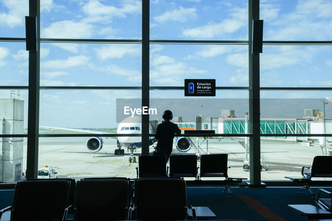 Rear view of man standing in waiting room at airport