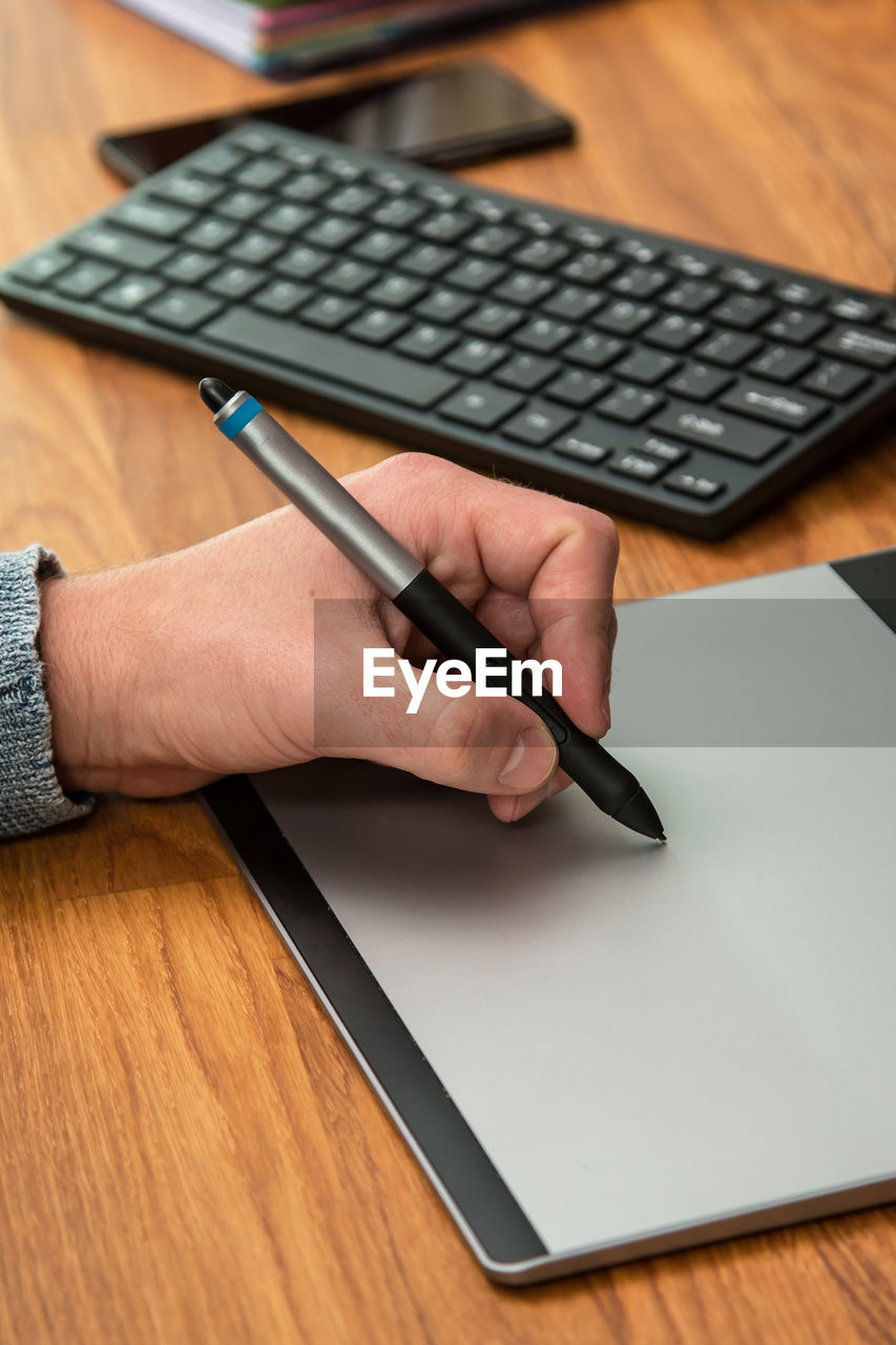 hand, computer, adult, desk, business, table, wireless technology, technology, one person, furniture, writing, indoors, working, pen, computer equipment, office, communication, laptop, business finance and industry, wood, computer keyboard, occupation, men, keyboard, high angle view, using computer, close-up, internet, computer mouse, place of work, office supplies, businessman, finance, paper, document, typing, computer network, mature adult