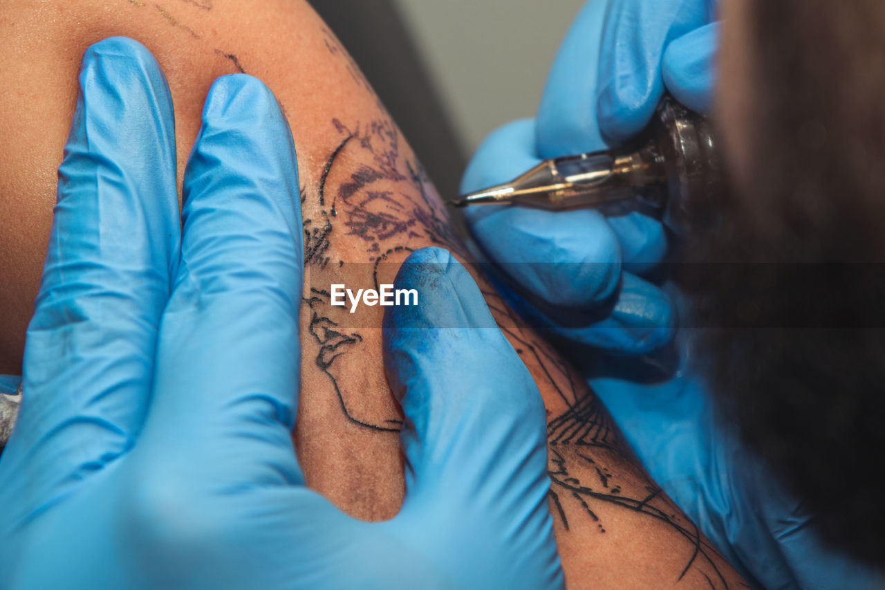 CLOSE-UP OF HUMAN HAND WITH TATTOO ON FLOOR