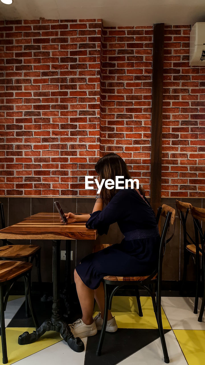 Women sitting on chair against wall