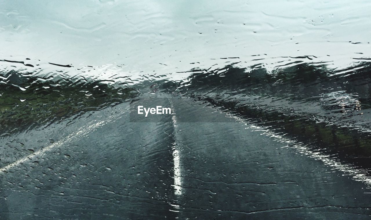 Road against sky seen through wet windshield during monsoon