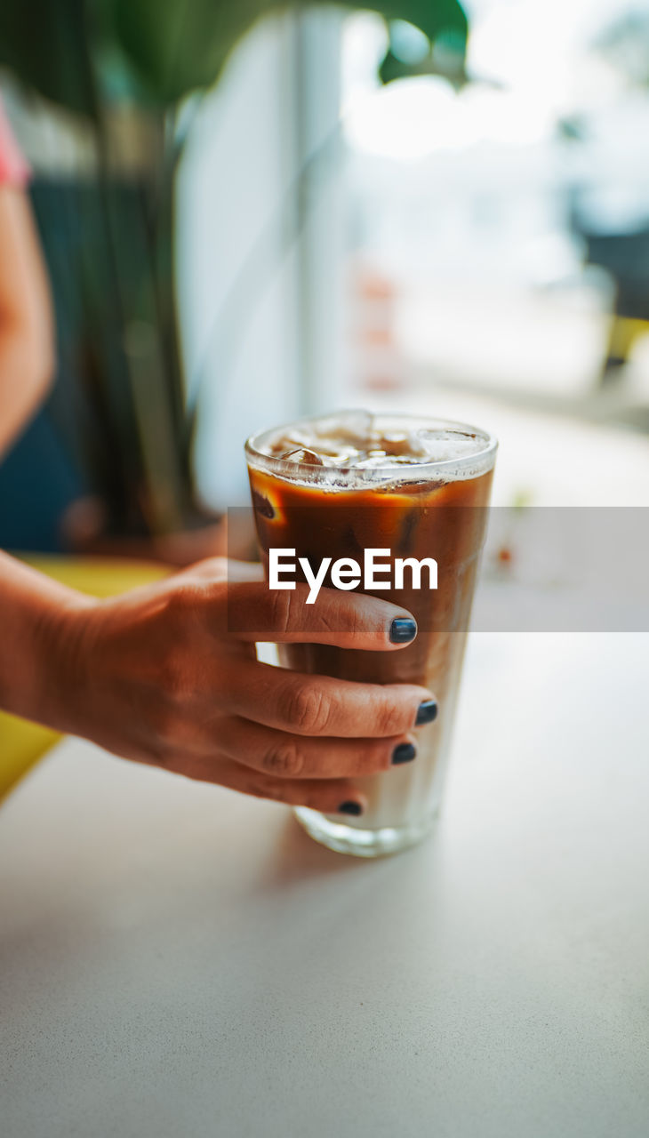 Cropped hand of woman with drink at table