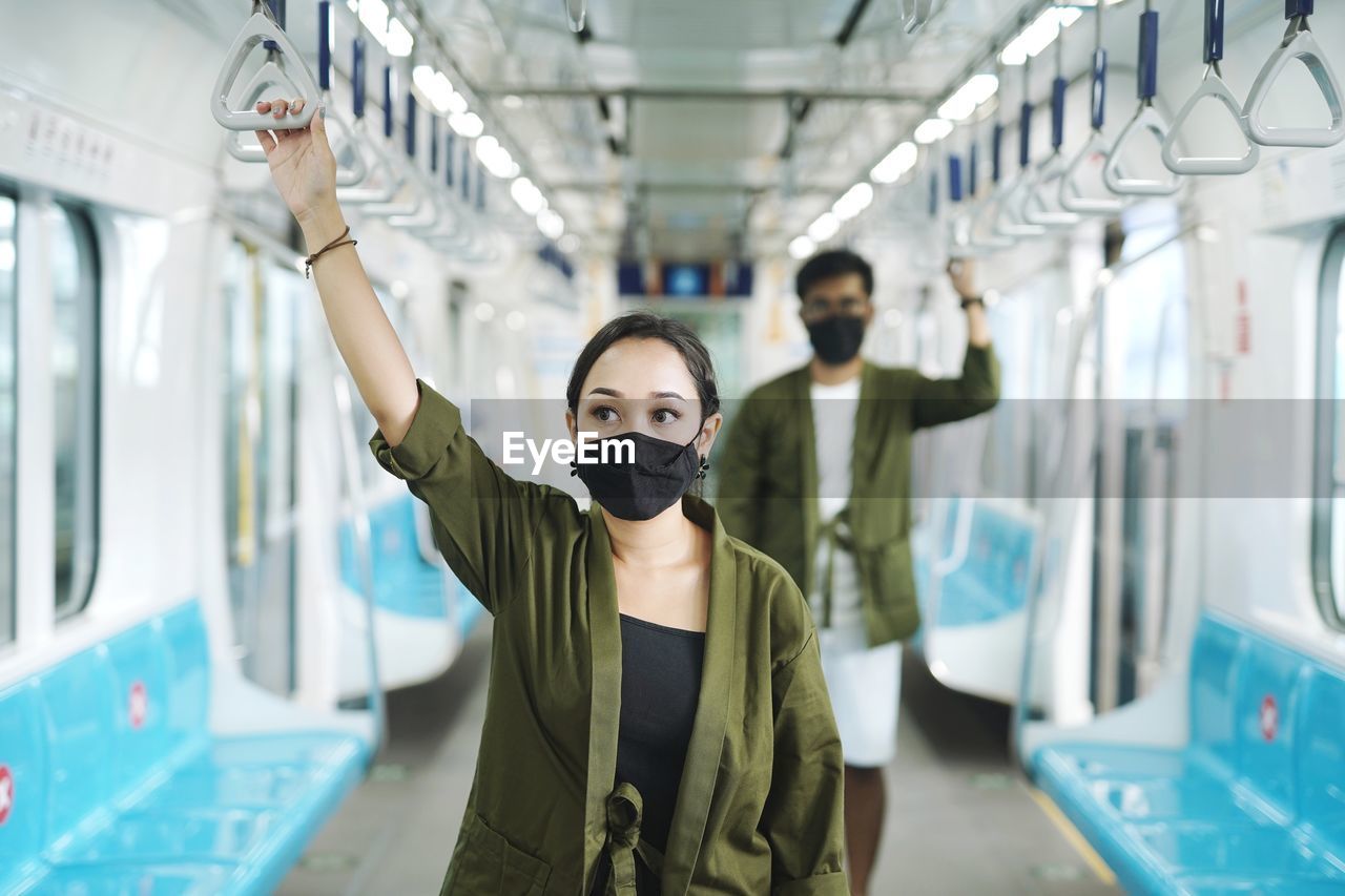 PORTRAIT OF YOUNG WOMAN STANDING ON BUS