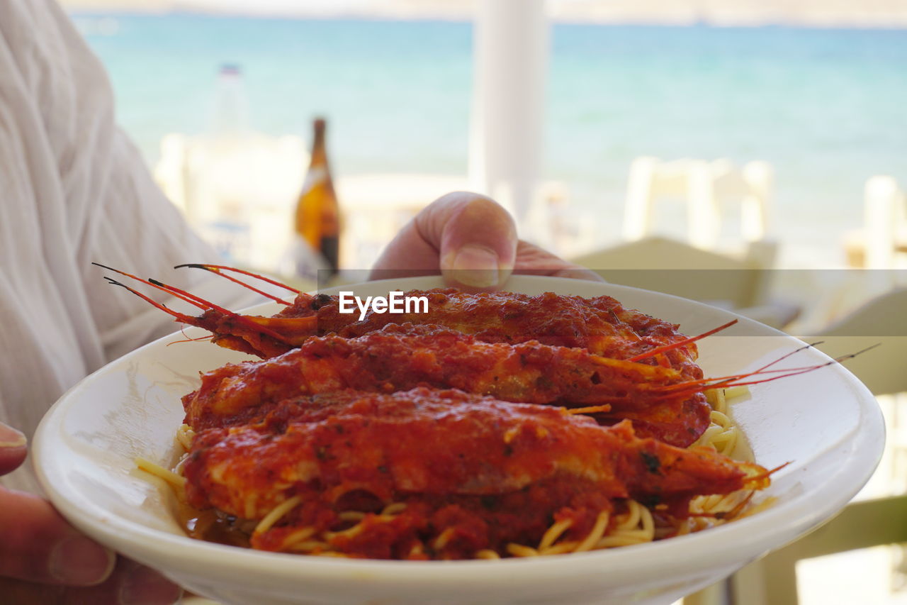 Cropped image of hands holding seafood in plate