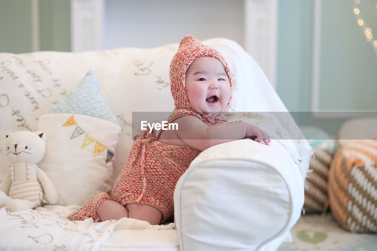 MIDSECTION OF CUTE BABY RELAXING ON BED AT HOME