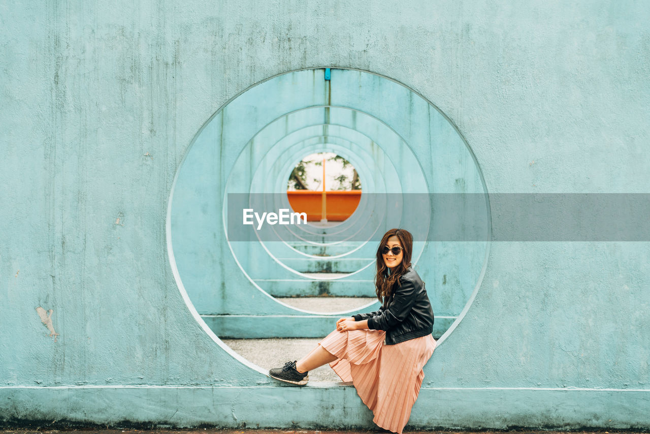 Woman sitting on hole in wall