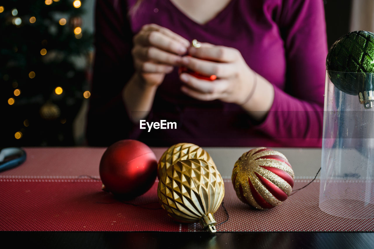 Midsection of woman making christmas baubles on table