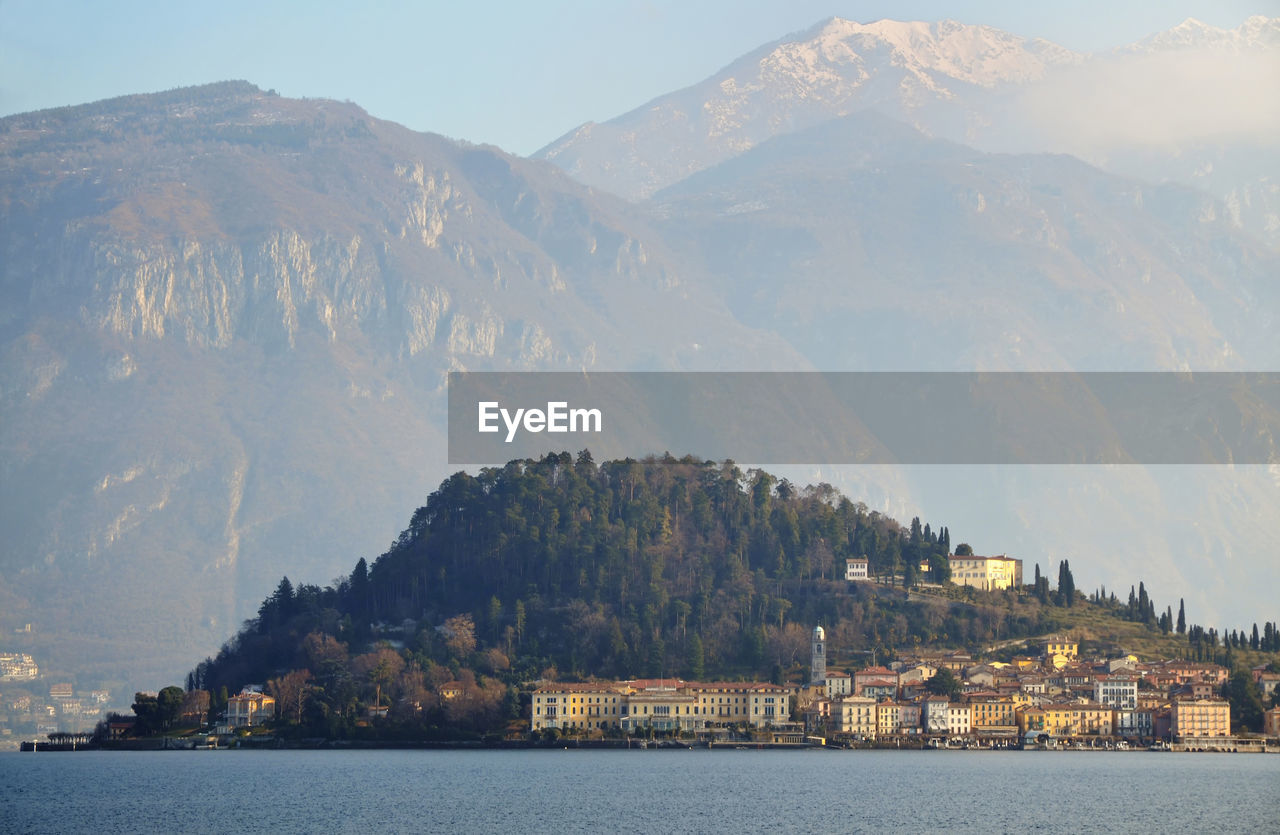 Scenic view of lake como by village against mountains