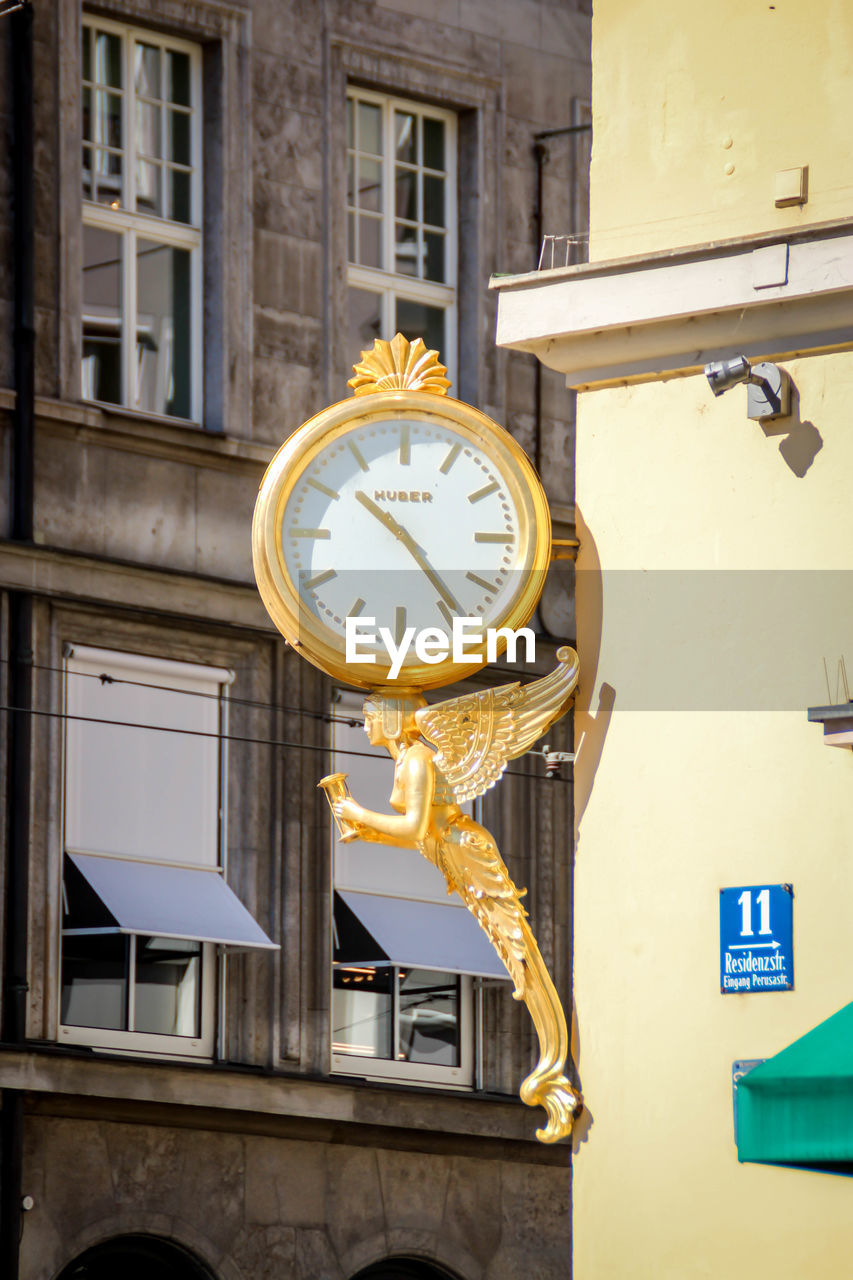 LOW ANGLE VIEW OF CLOCK AGAINST BUILDINGS