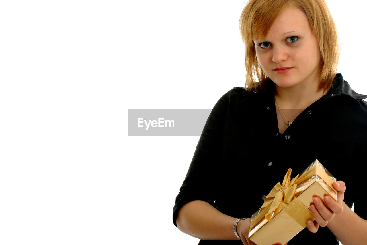 Portrait of young woman holding gift over white background