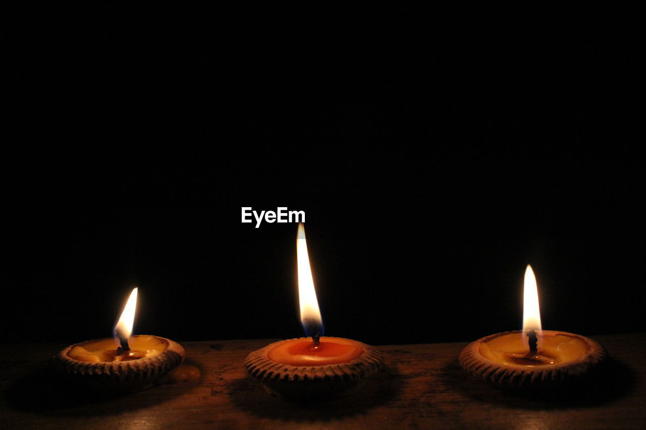 Close-up of lit diyas against black background